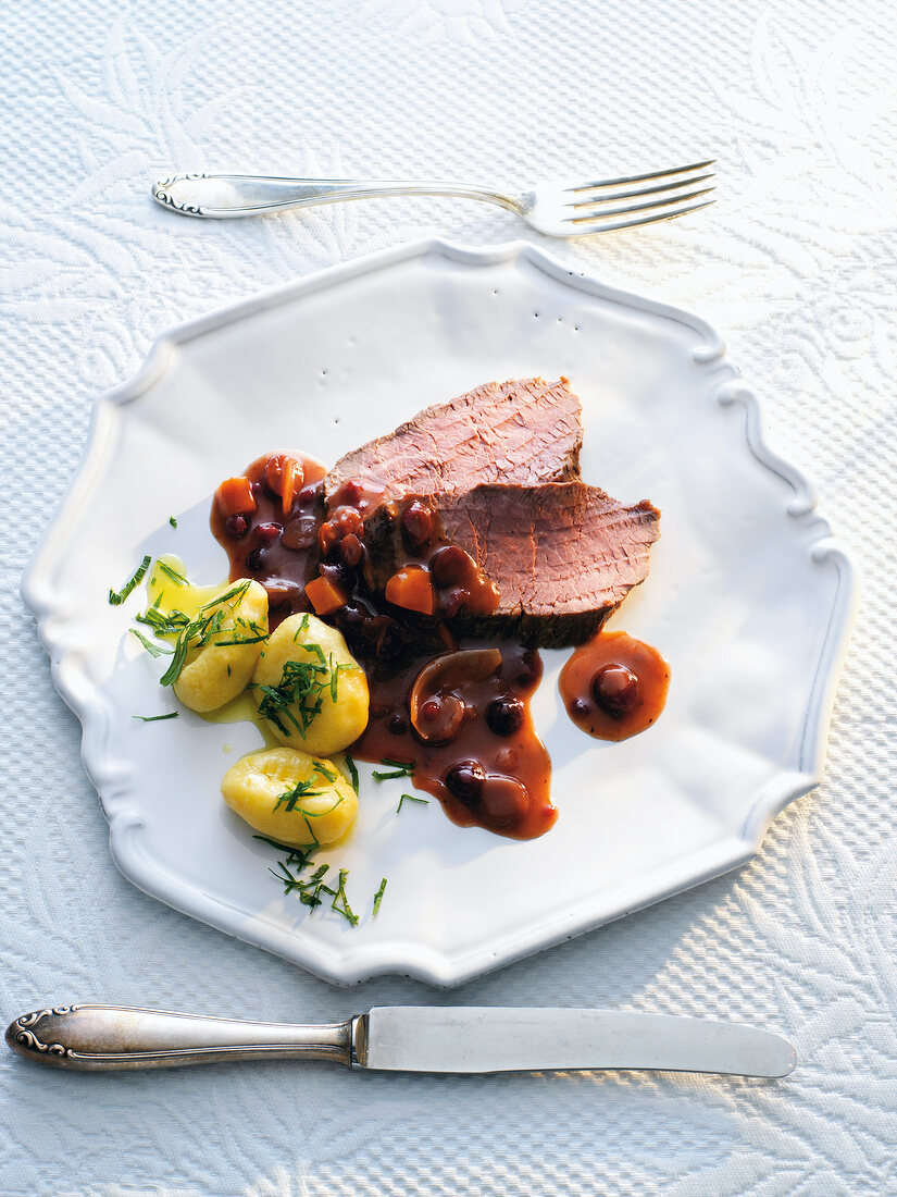 Fillet with sauerbraten sauce and cranberries on plate