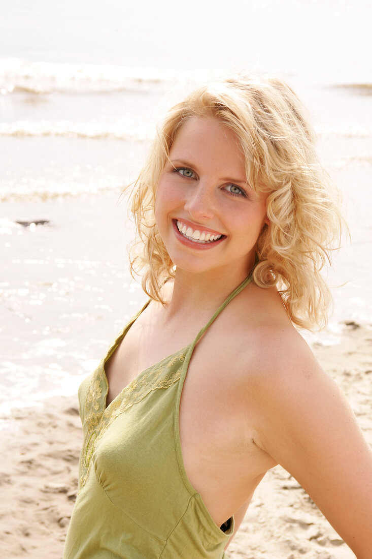 Portrait of beautiful blonde woman wearing green halter top, smiling