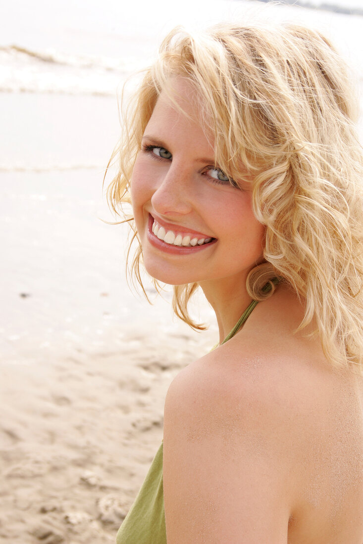 Portrait of beautiful blonde woman wearing green halter top, smiling