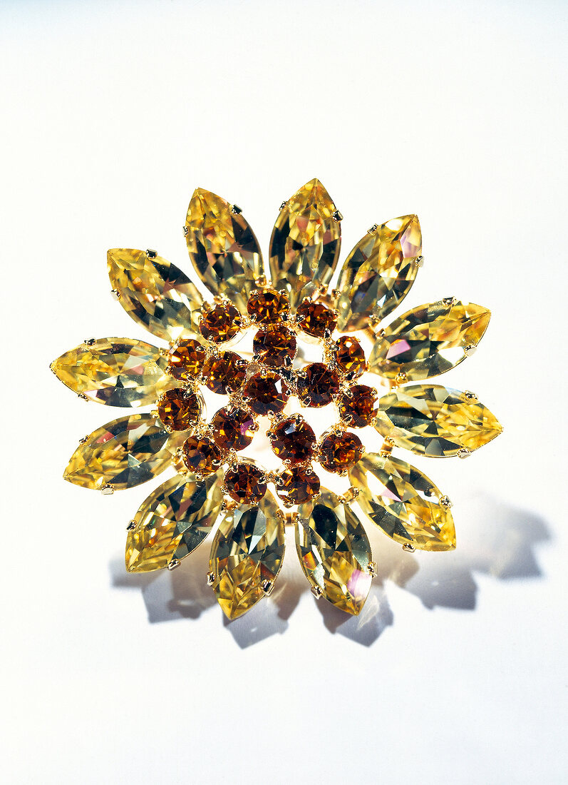 Close-up of yellow and red flower shaped brooch on white background