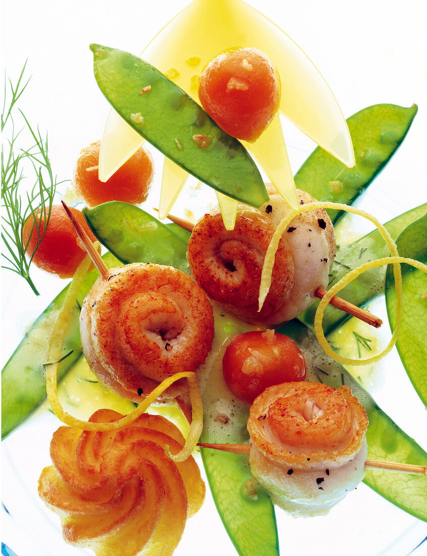 Close-up of fillet of sole with snow peas, glazed carrots and lime butter on plate