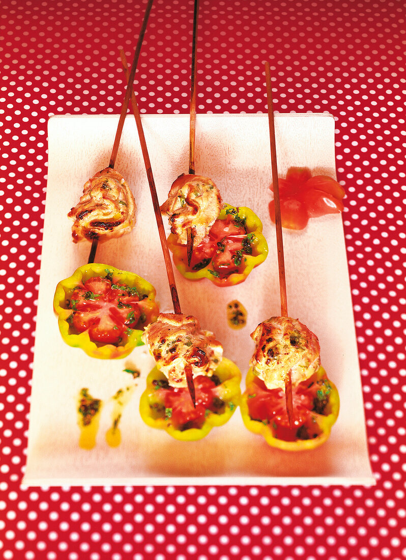 Marinated pig fillet on skewers and tomato on plate