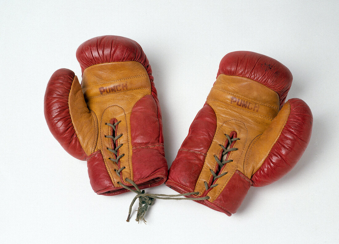Pair of red and yellow boxing gloves tied together on white background