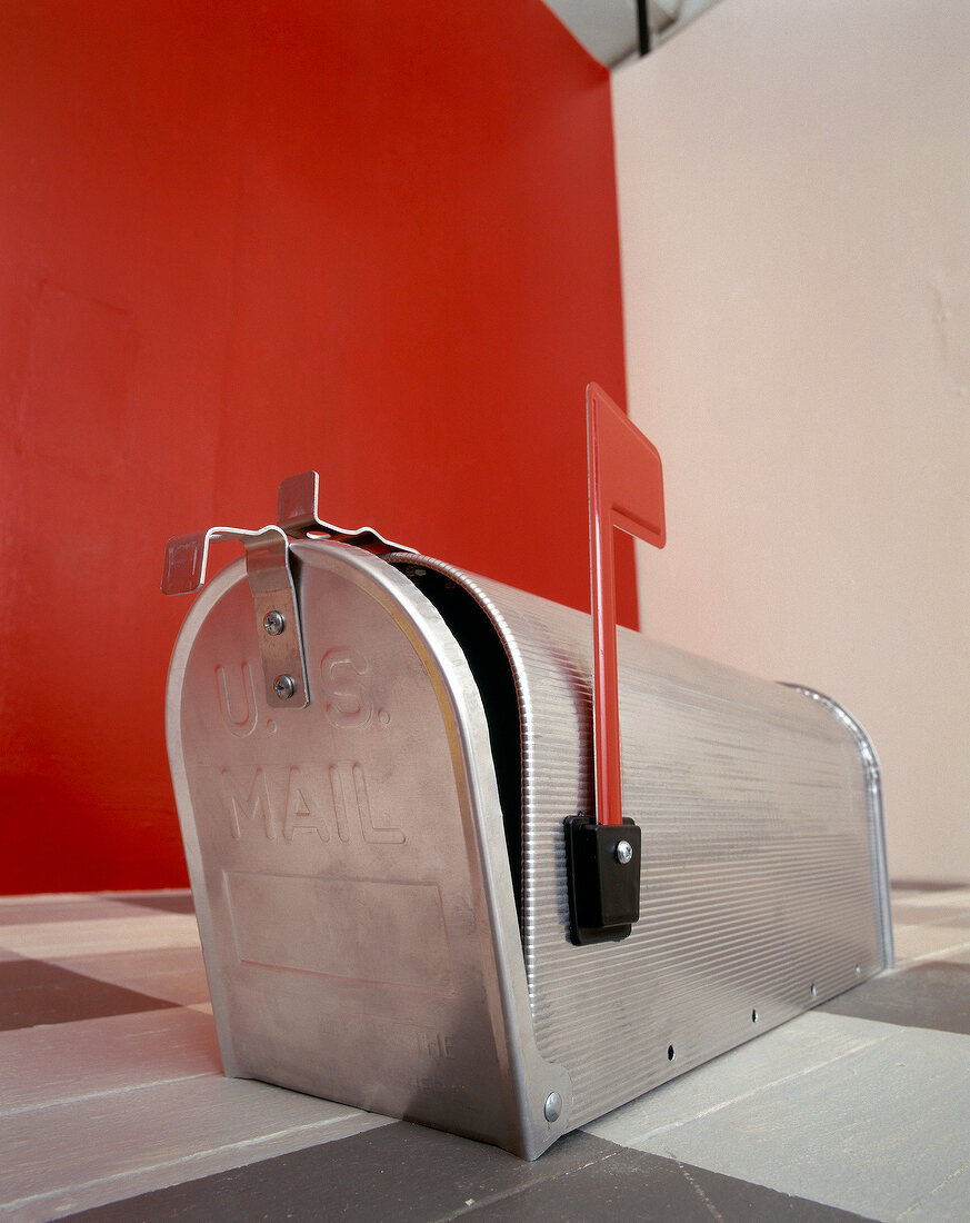 Metal mailbox with red flags on checked tile floor