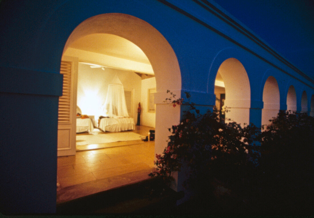 View of illuminated bedroom with arcade in villa at night, Jamaica