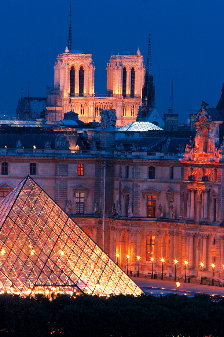 View of illuminated Notre Dame Cathedral and Louvre Pyramid at night, Paris, France