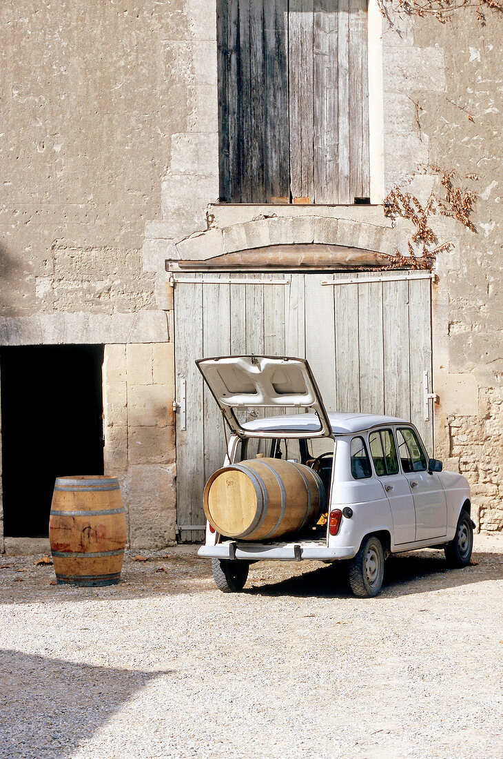 Old Renault in front of vineyard laden with wine barrel in trunk