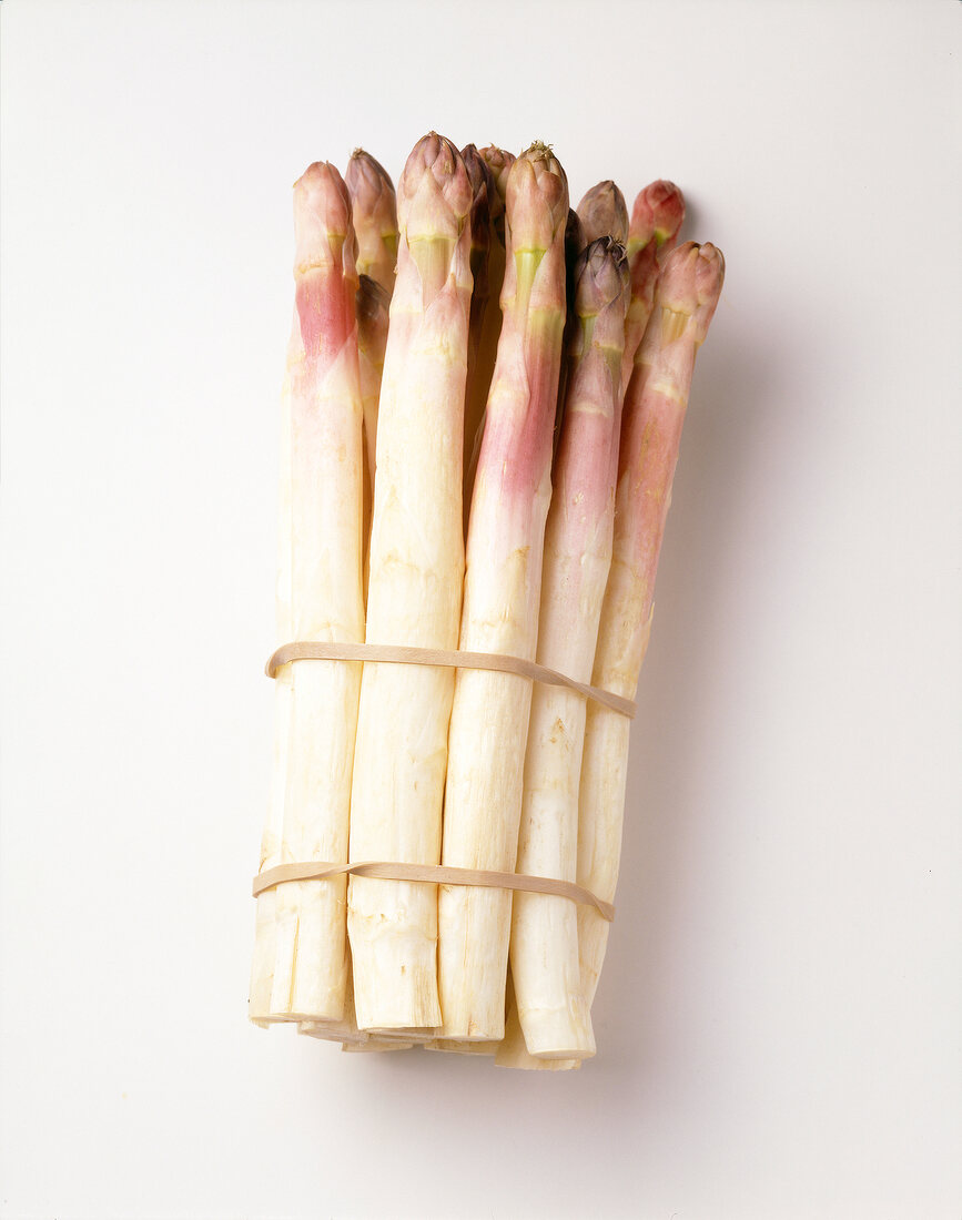 Bunch of asparagus with pink tips on white background