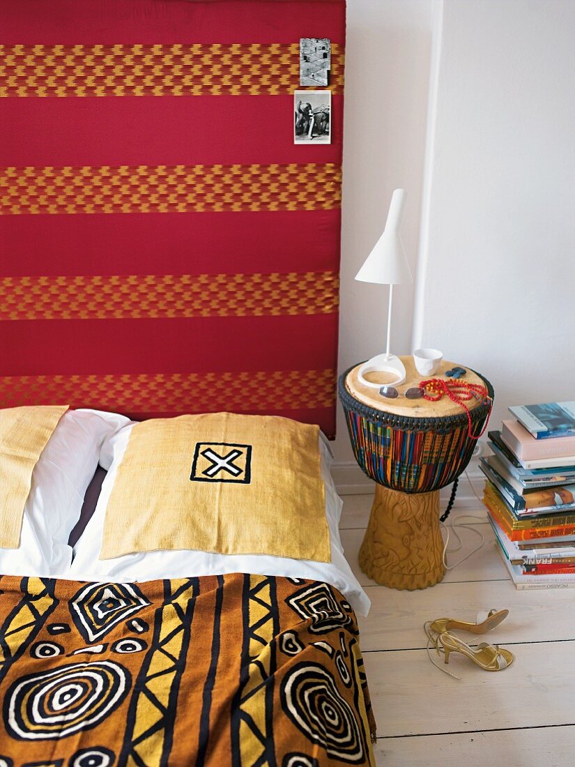 An ethnic-style bedroom with patterned bedclothes and a drum as bedside table