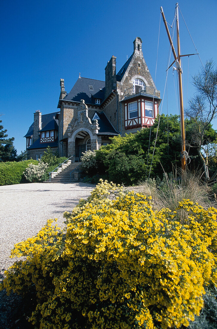 Low angle view Castle Hotel and yellow flowers in Chateau Richeux at Cancale, France