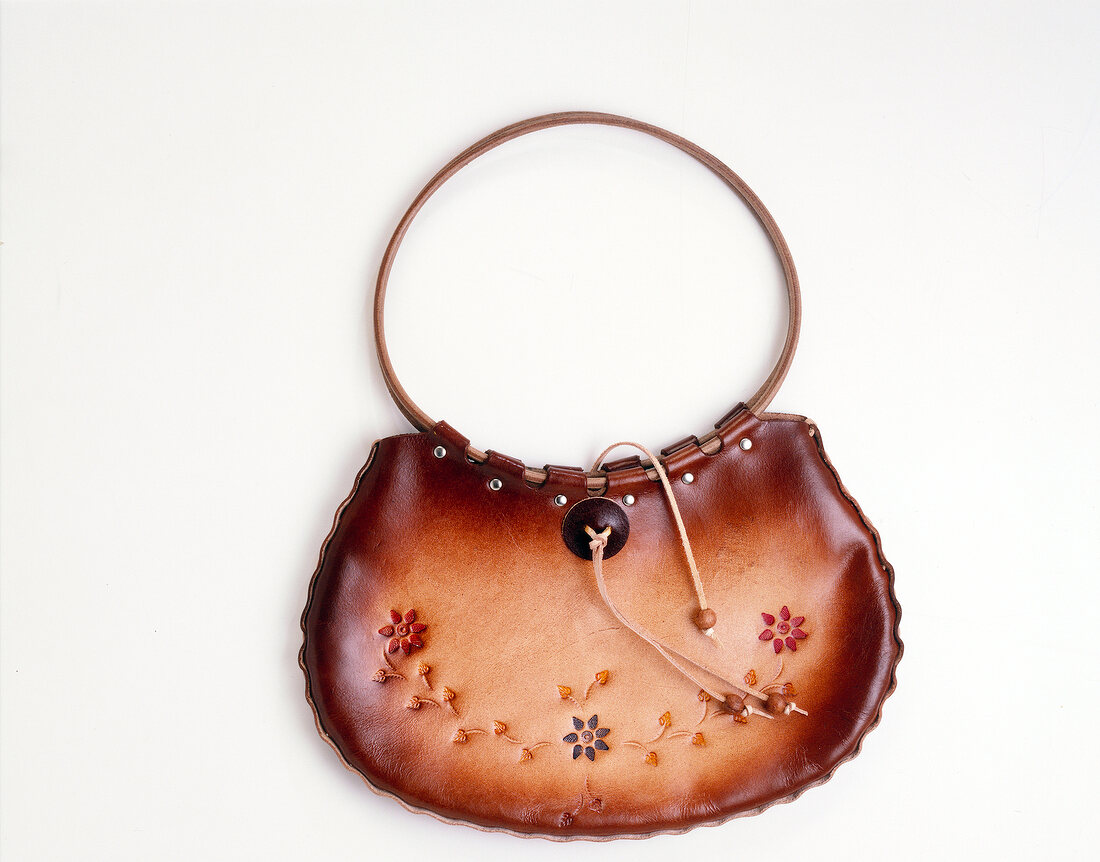 Close-up of brown handbag with floral pattern on white background