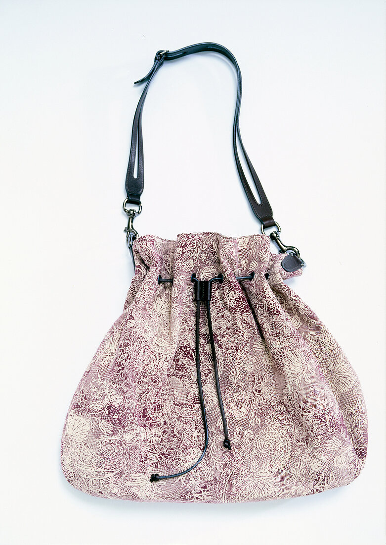 Close-up of pouch handbag with floral motif on white background