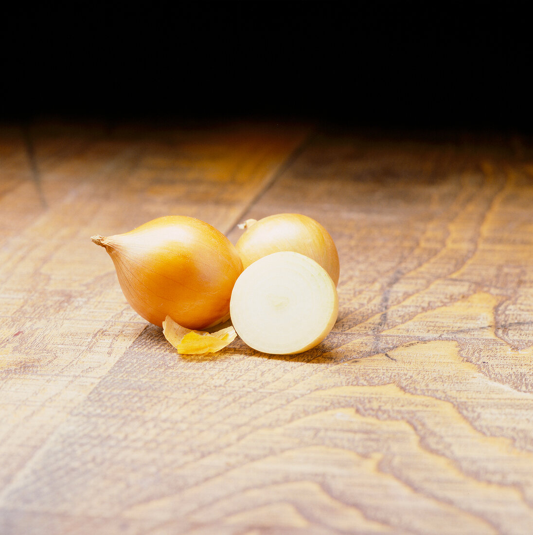 Whole and halved onion on wooden table