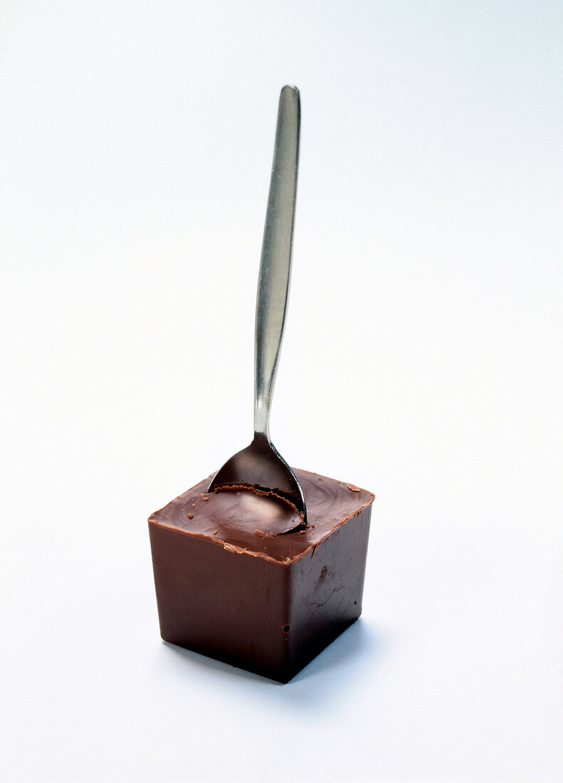 Chocolate cube with silver teaspoon on white background