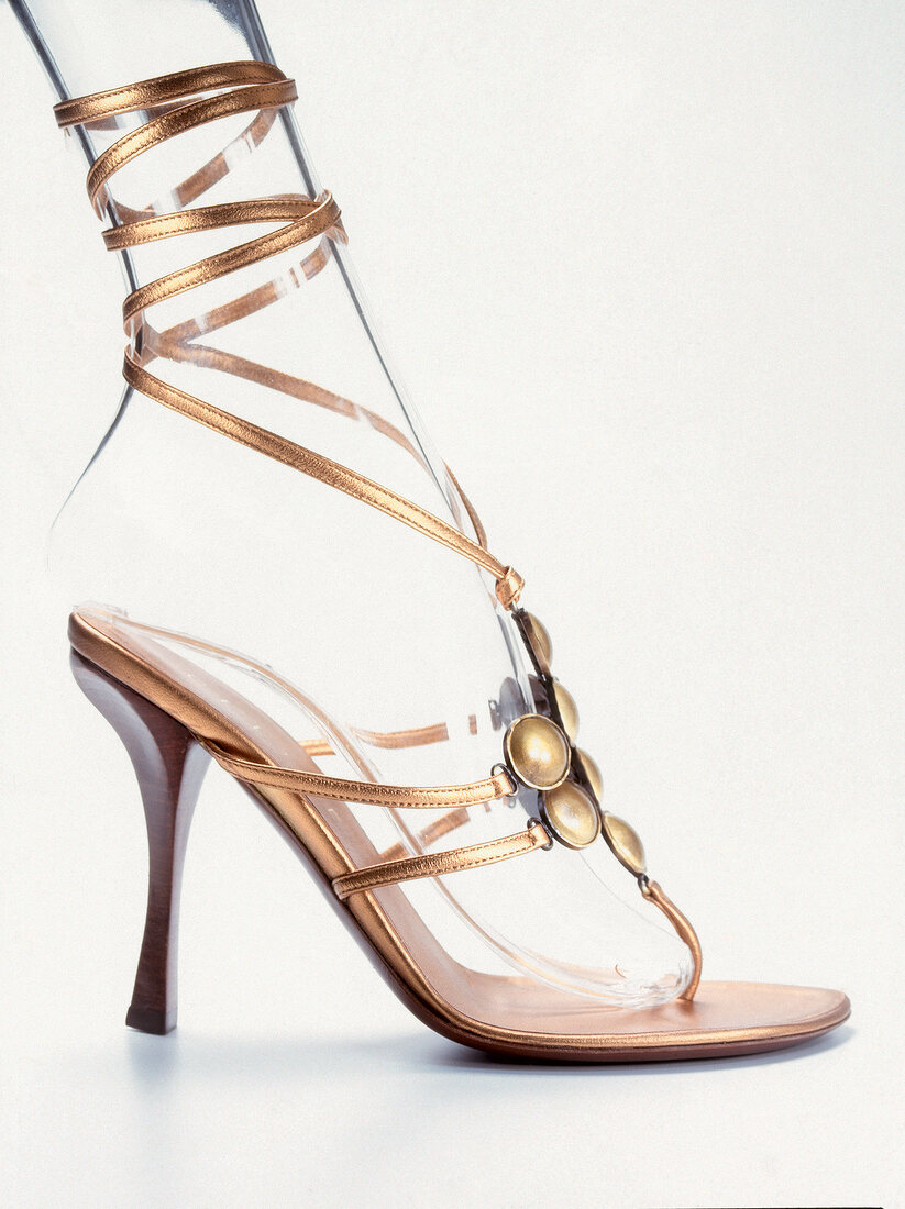 Close-up of golden high heels with ribbons on white background
