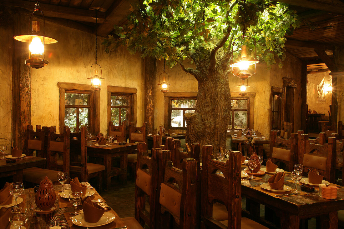 Laid tables and chair with artificial tree in Shinok Restaurant, Moscow, Russia