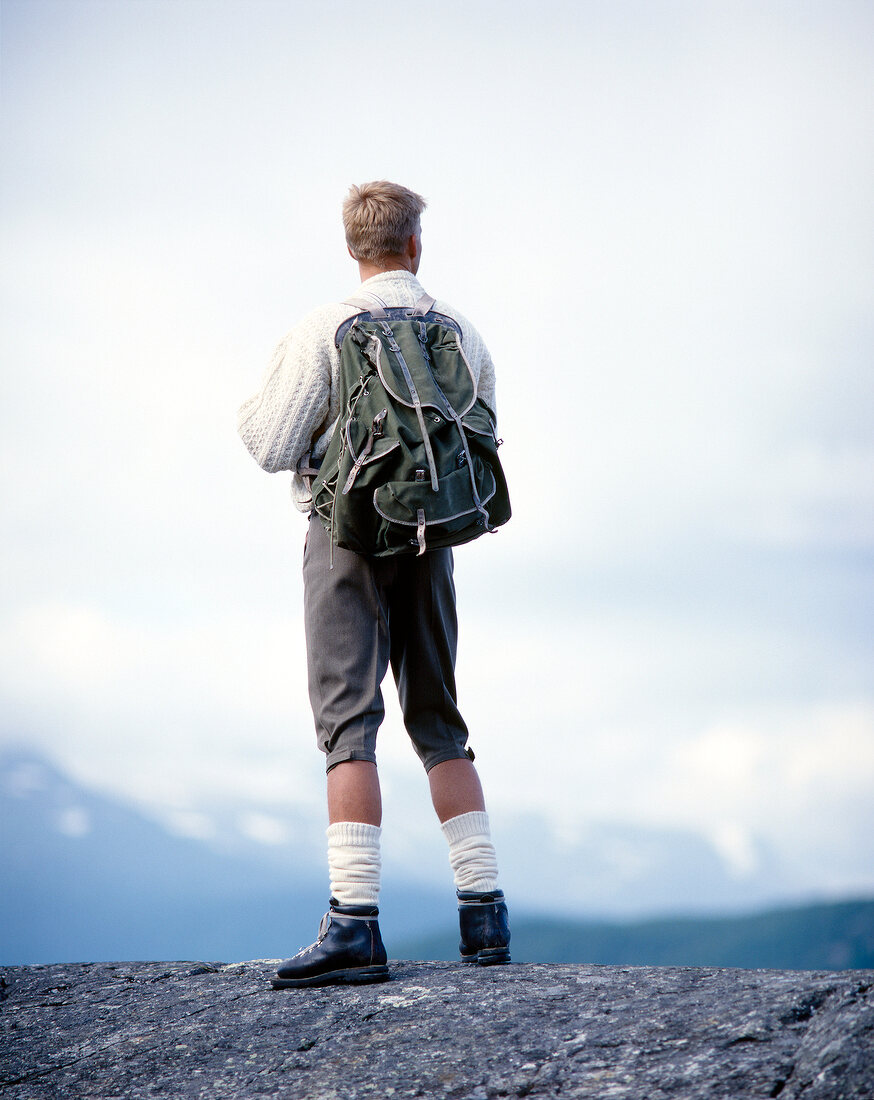 Rear view of man with hiking bag looking at view from top of mountain