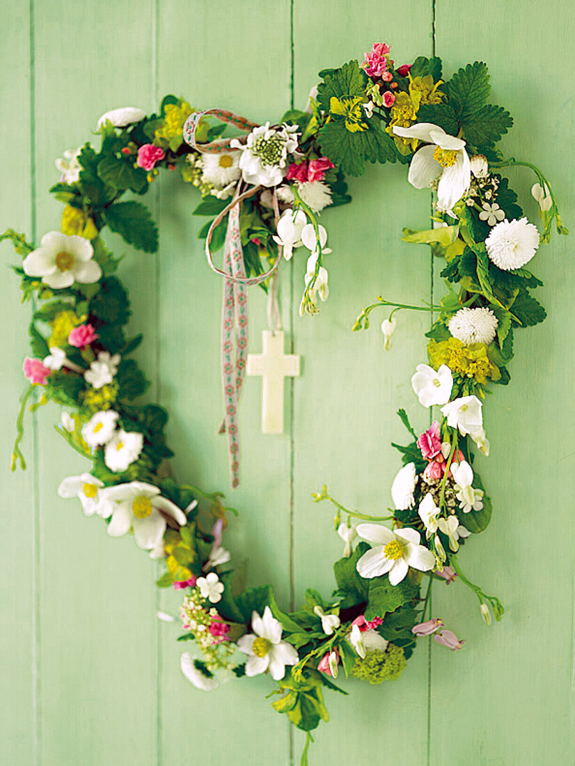 Flower arrangement in the shape of a heart made of spring flowers, with a cross