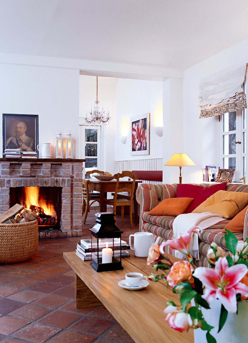 Living room with fire place, sofa, cushion and flower vase on wooden table