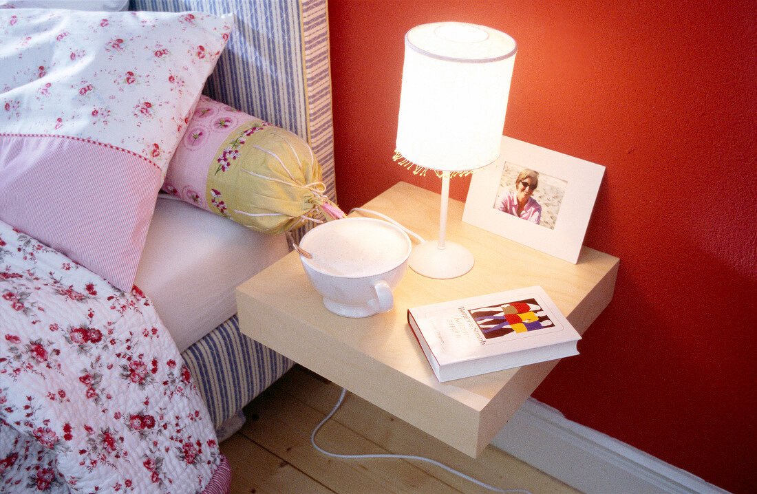 Cup, book and lamp on beige side table