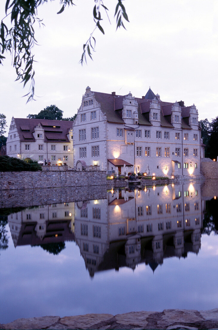 Reflection of Schloss hotel Munchhausen in pond at dusk