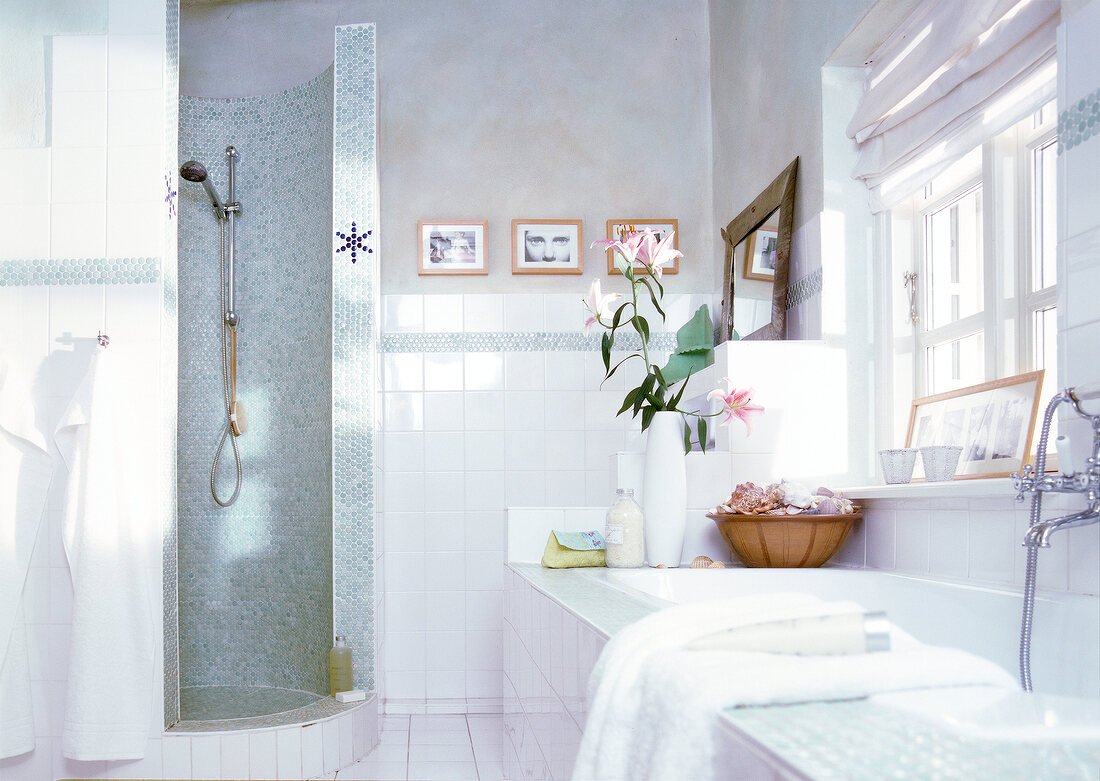 View of white tiled bathroom with shower and bathtub