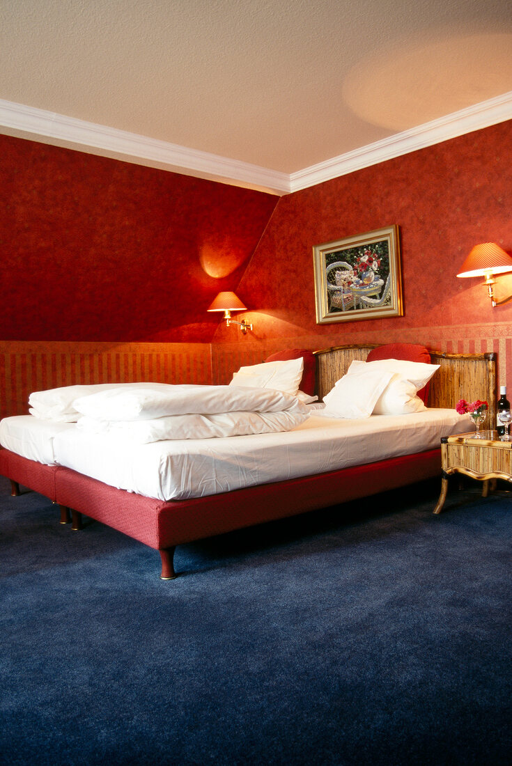 Zimmer im Hotel, Bett und Wände rot, beleuchtet.