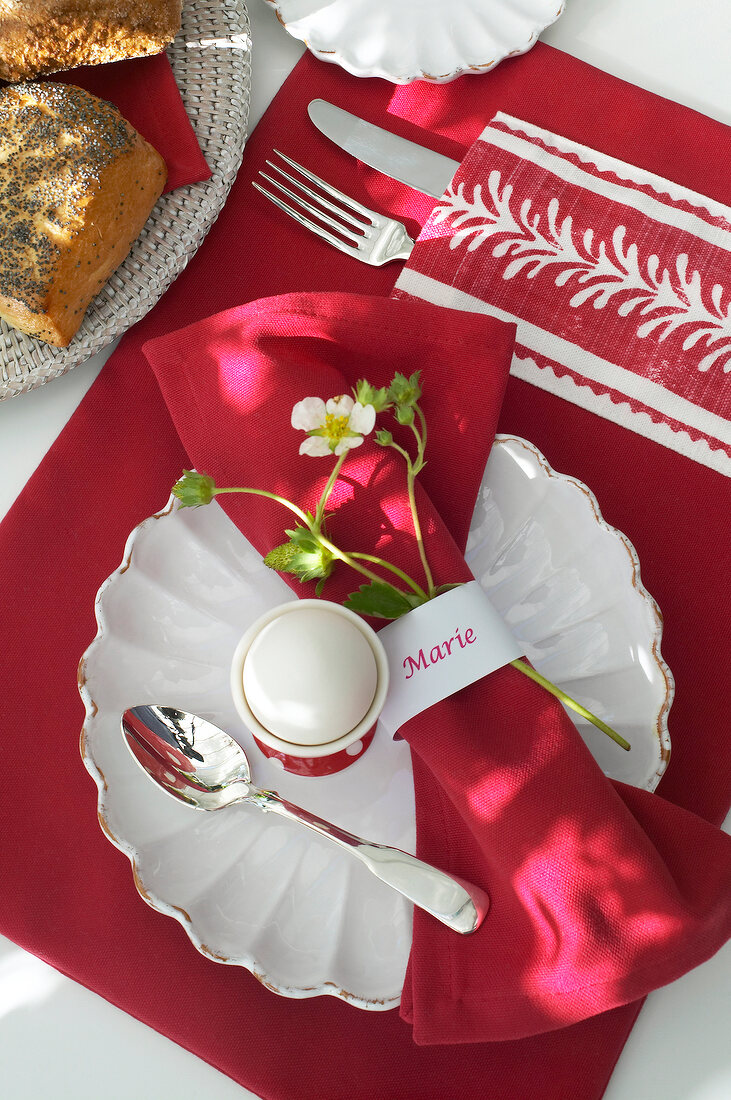 Napkin rolled in red placeholder for Marie decorated at breakfast table with flower