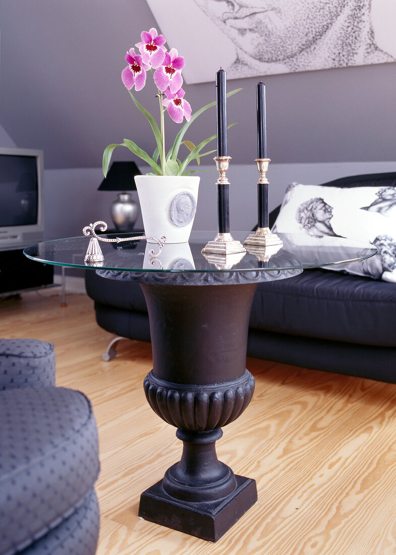 Living room with coffee table with glass top and flower vase with orchid on top