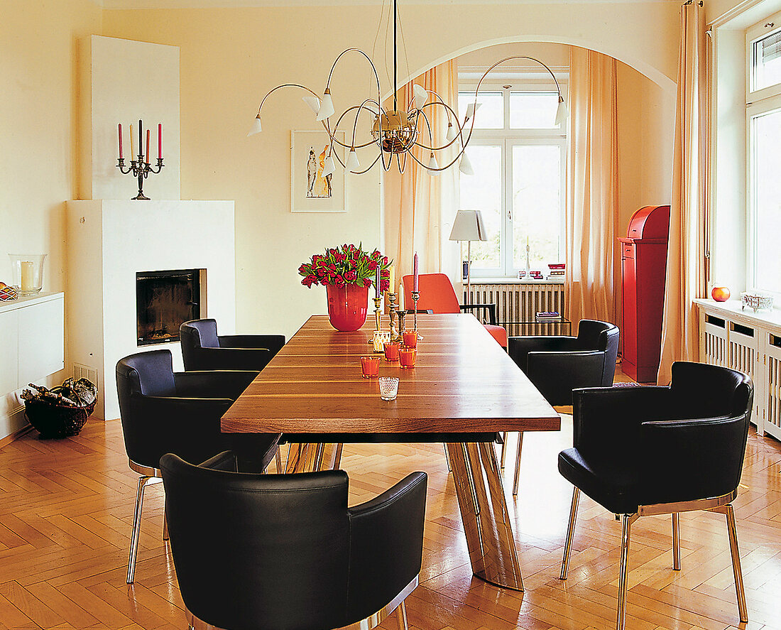 Esszimmer mit Kamin, langer Tisch und schwarze Sesselstühle.