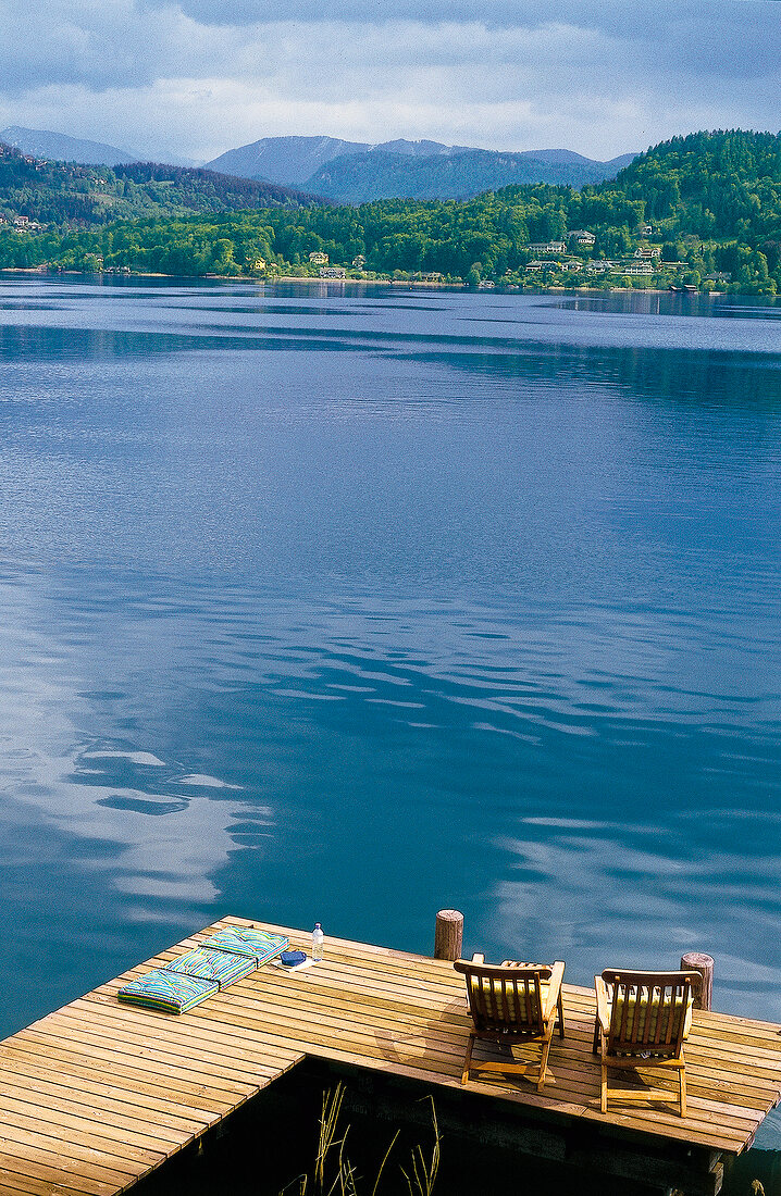 View of dock with chairs in front of Lake Worthersee, Austria