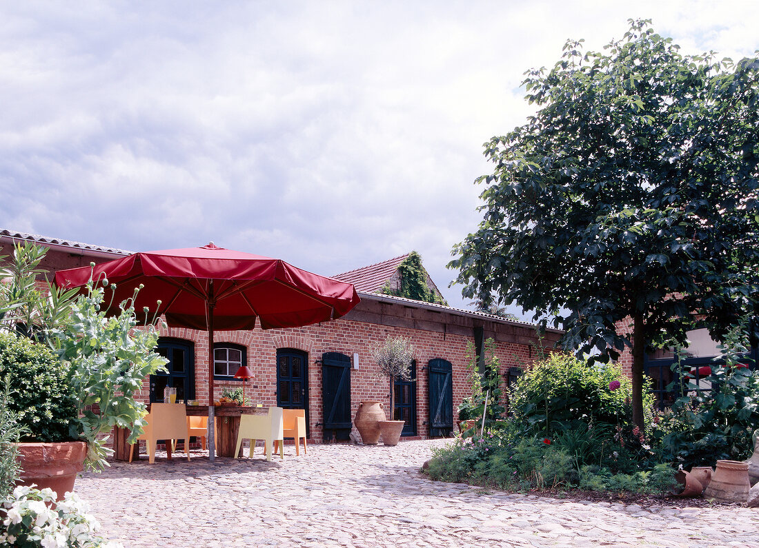 Exterior of building with paved patio and red parasol