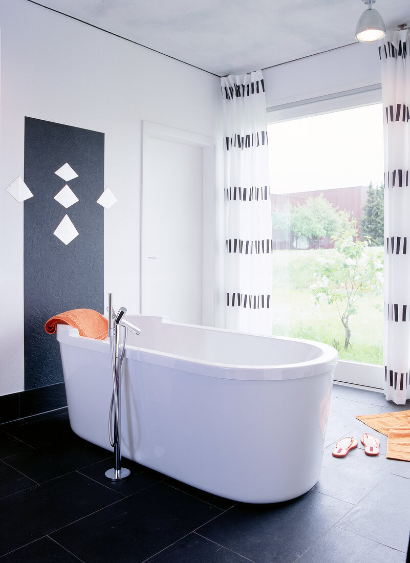 Free standing bathtub in centre of bathroom in front of big window