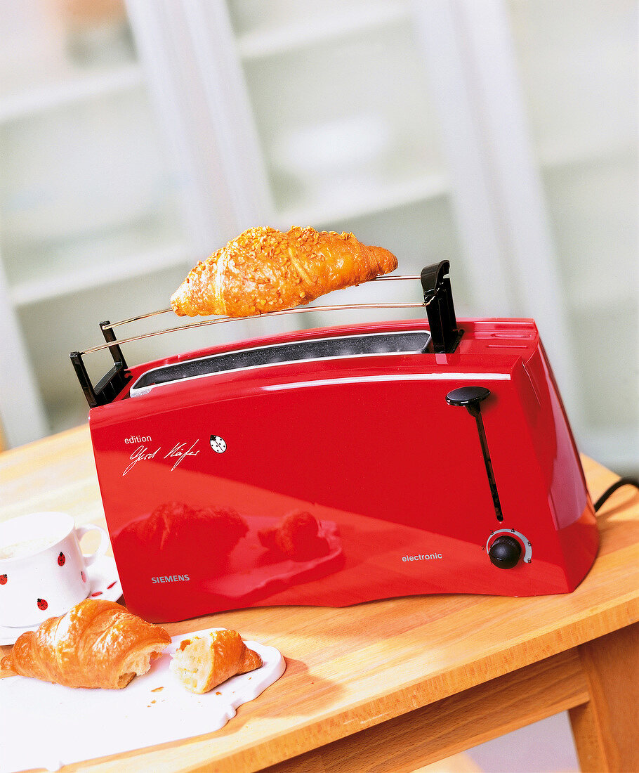 Red toaster with croissant above