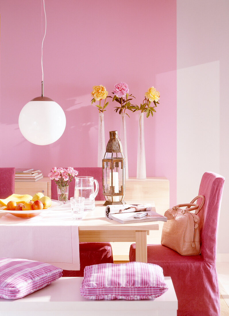 Essplatz in rosa mit Vasen auf Regal vor rosa Wand