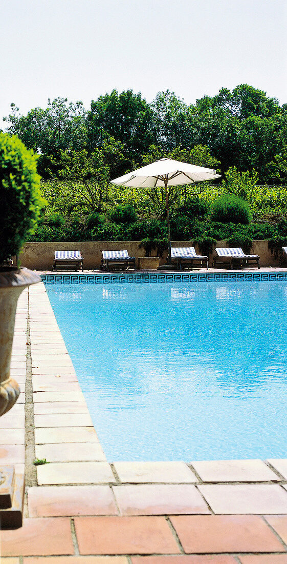 Sun loungers and umbrellas beside swimming pool at Chateau Hermitage de Combas, France