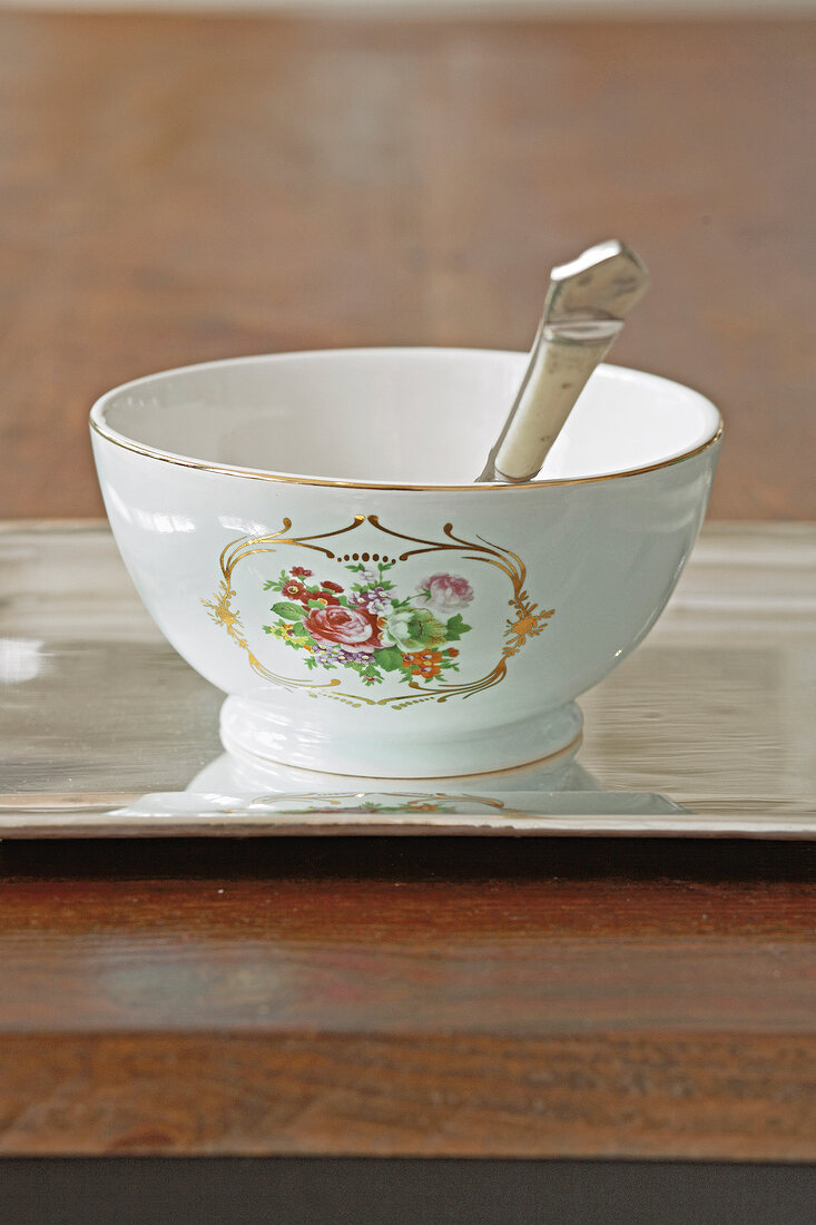 Close-up of cereal bowl with floral pattern and gold rim on tray