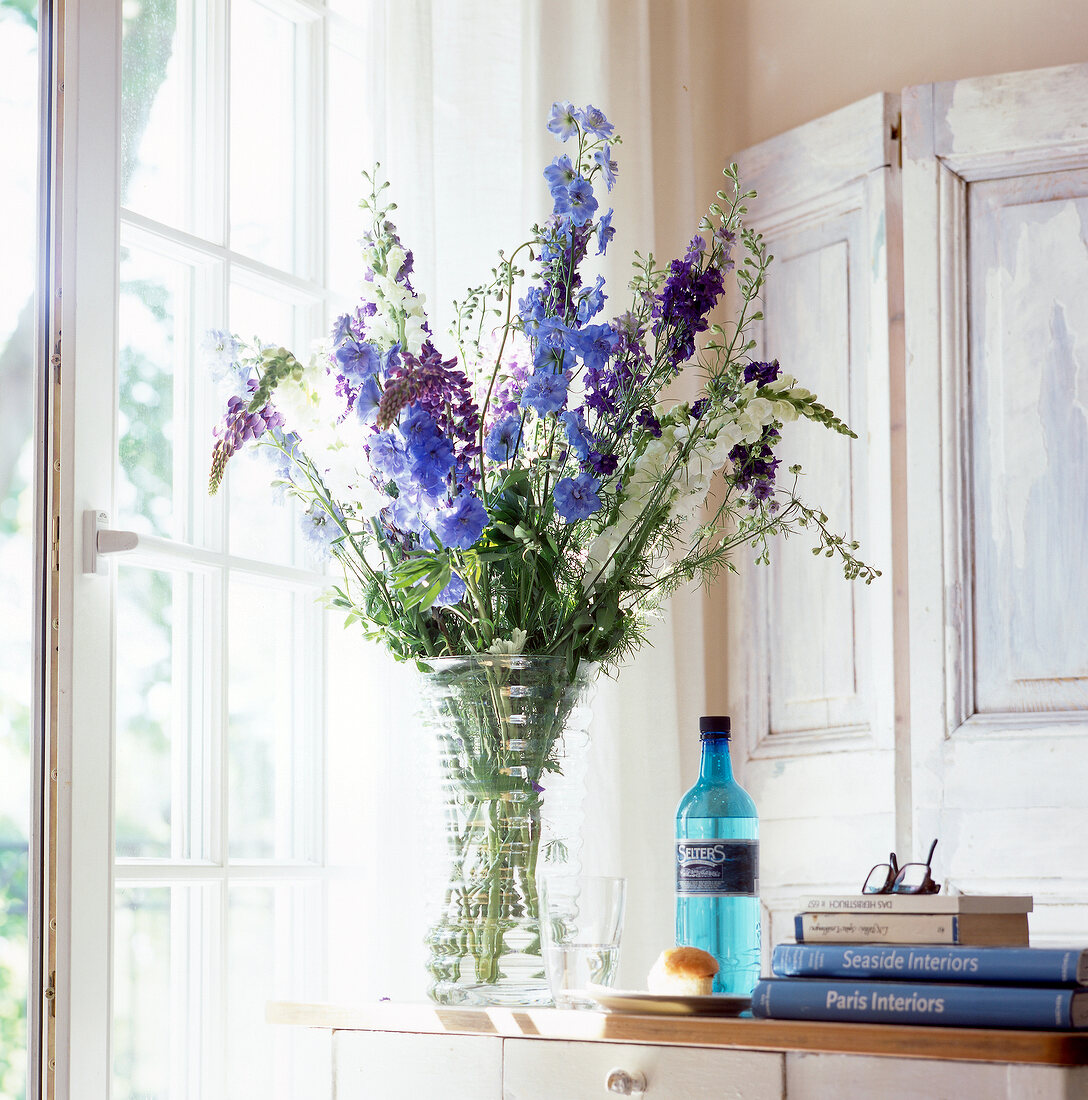 Bouquet of violet coloured flowers in vase on sideboard