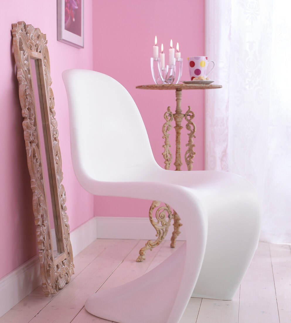 White modern chair and mirror with frame in room with pink walls