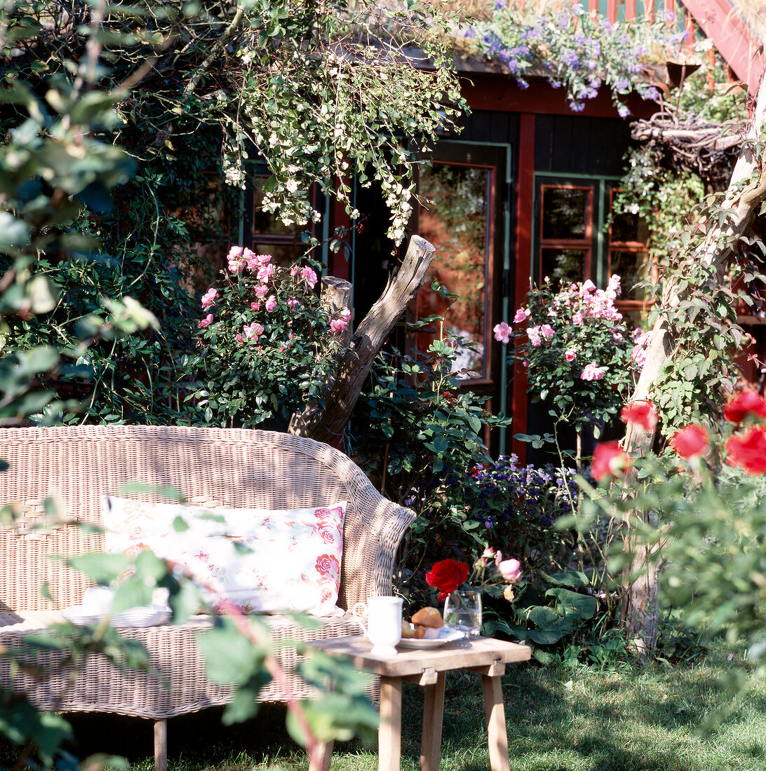 Rattan sofa and small coffee table in garden in front of house