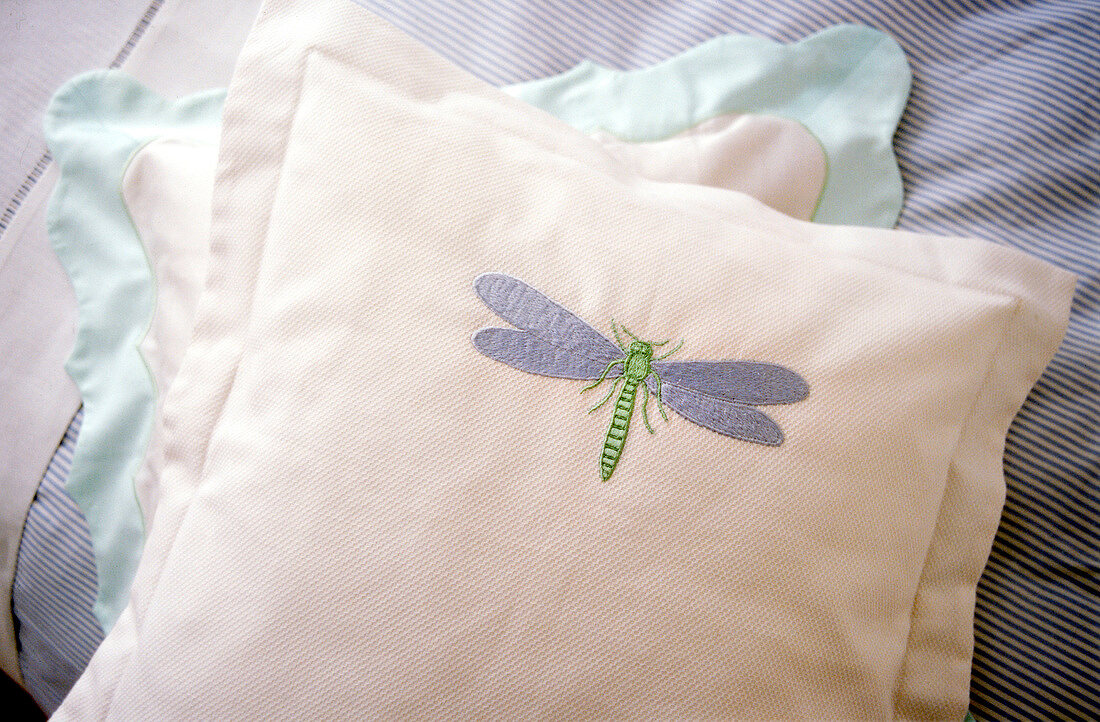 Close-up of blue and white cushion with embroidery of dragonfly