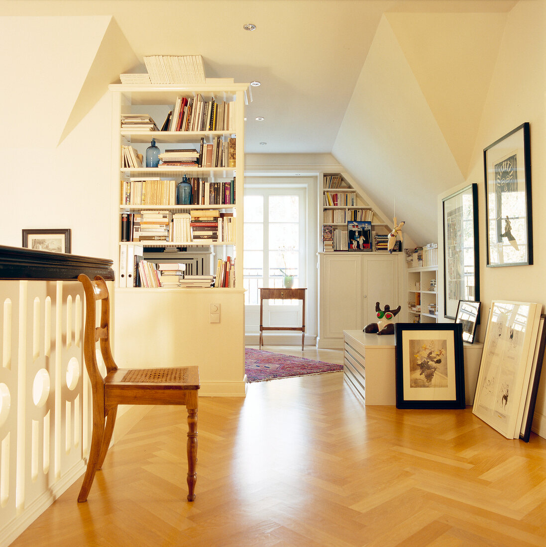 View of living room with framed pictures on wall, chair and parquet flooring