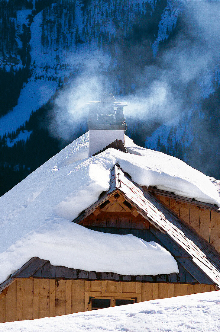 Chimney and snow covered roof of wooden hut