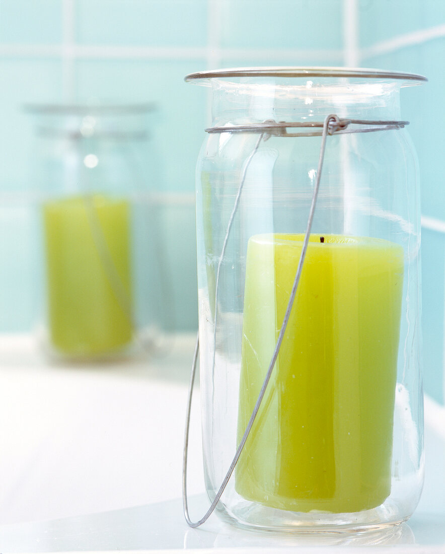 Close-up of light green candle in glass jar with metal handle