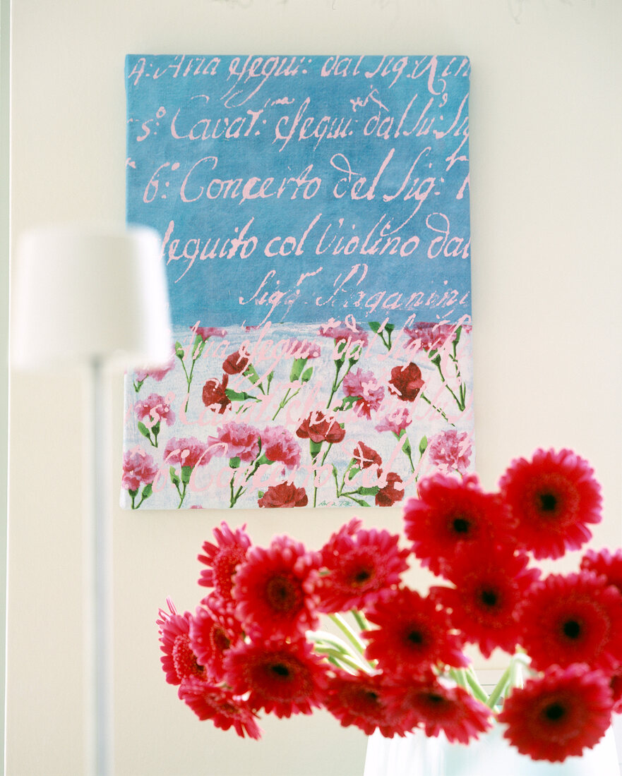 Close-up of red gerberas in front of handwritten picture with floral motifs