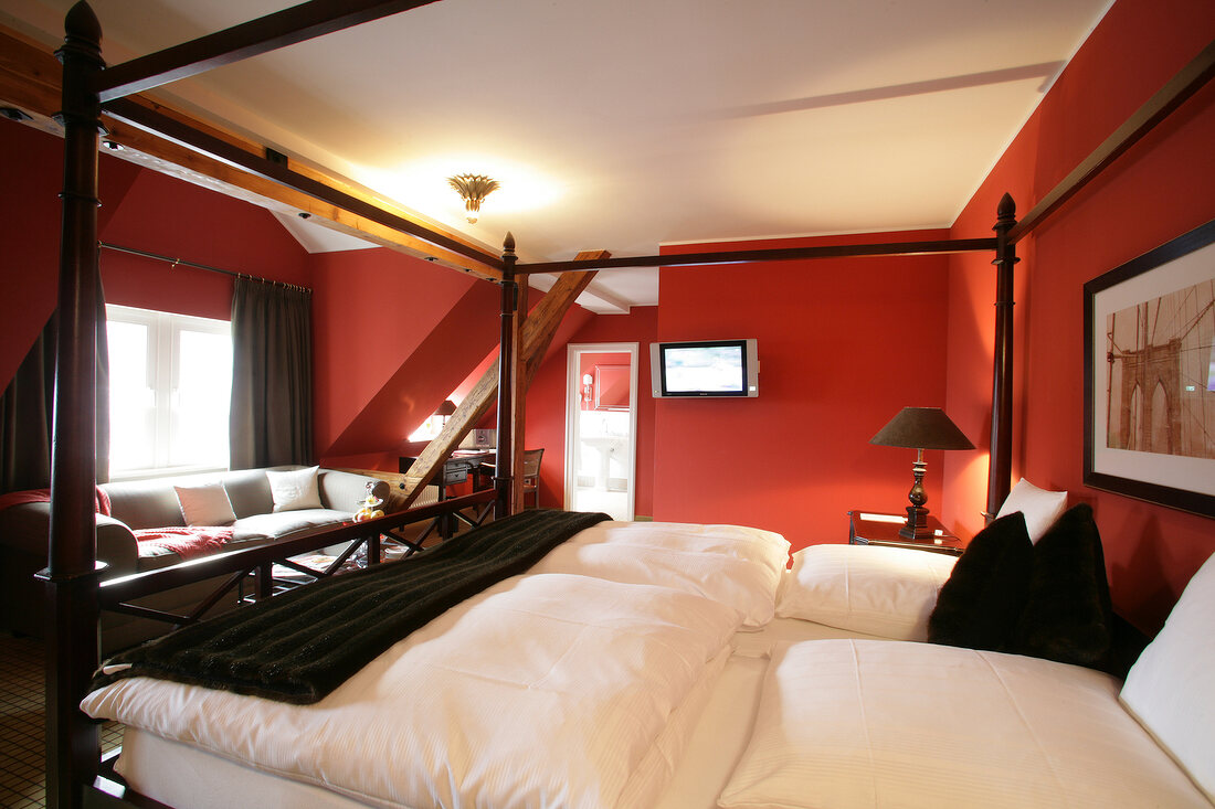 Bedroom with poster bed, cushion and sofa in hotel, Germany