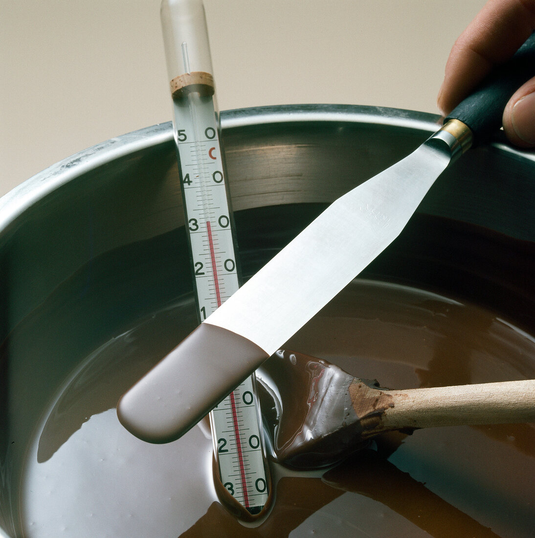 Close-up of thermometer in vessel of melted chocolate to check temperature