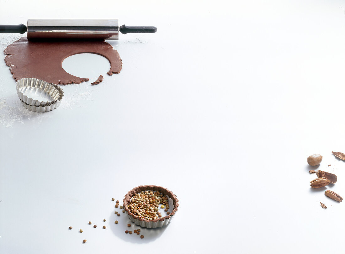 Chocolate dough, rolling pin, cake pan and lenses on white background, copy space