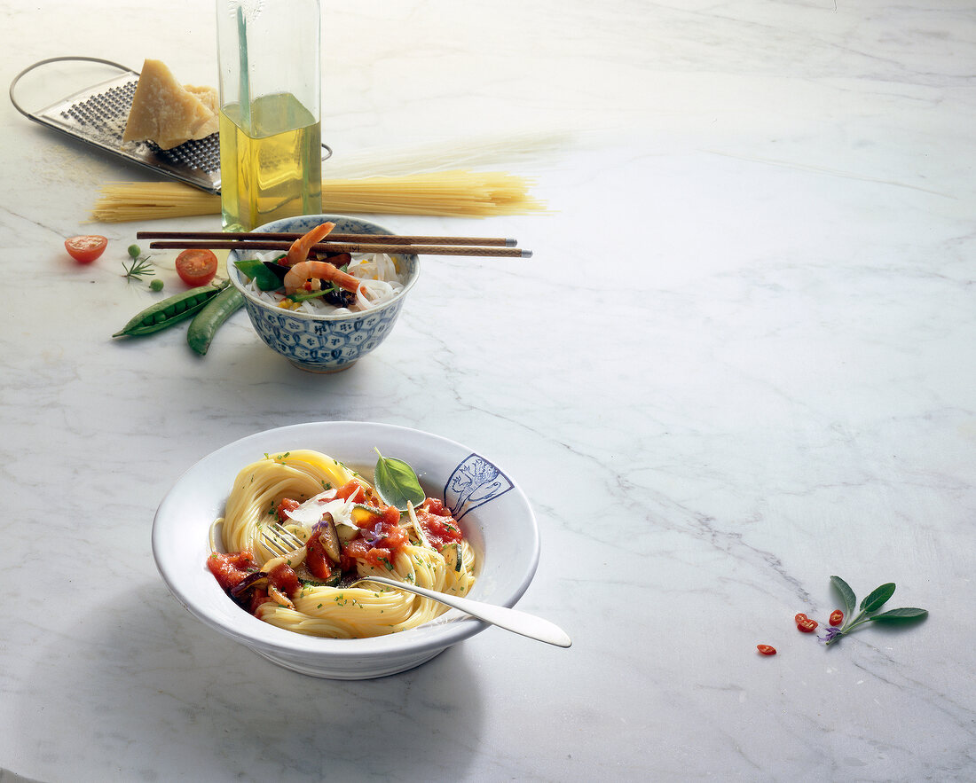 Spaghetti in bowl with ingredients on white background