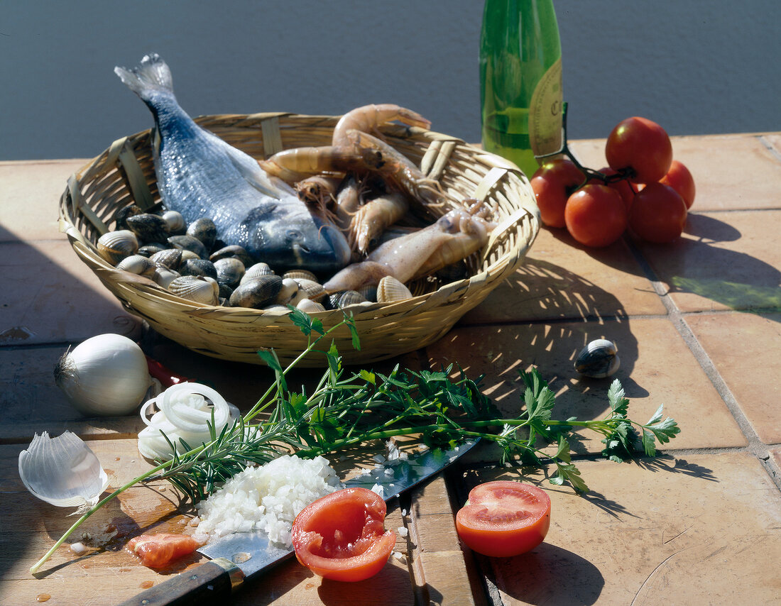 Basket of seafood beside vegetables and herbs